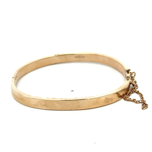 9ct yellow gold bangle weighing 24.1g, stylish jewelry piece with smooth polished finish, designed by Reeves and Sons.