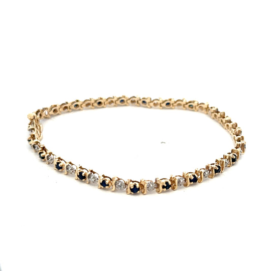 Reeves and Sons 9ct yellow gold sapphire and diamond bracelet showcasing blue sapphires and sparkling diamonds on a gold chain.