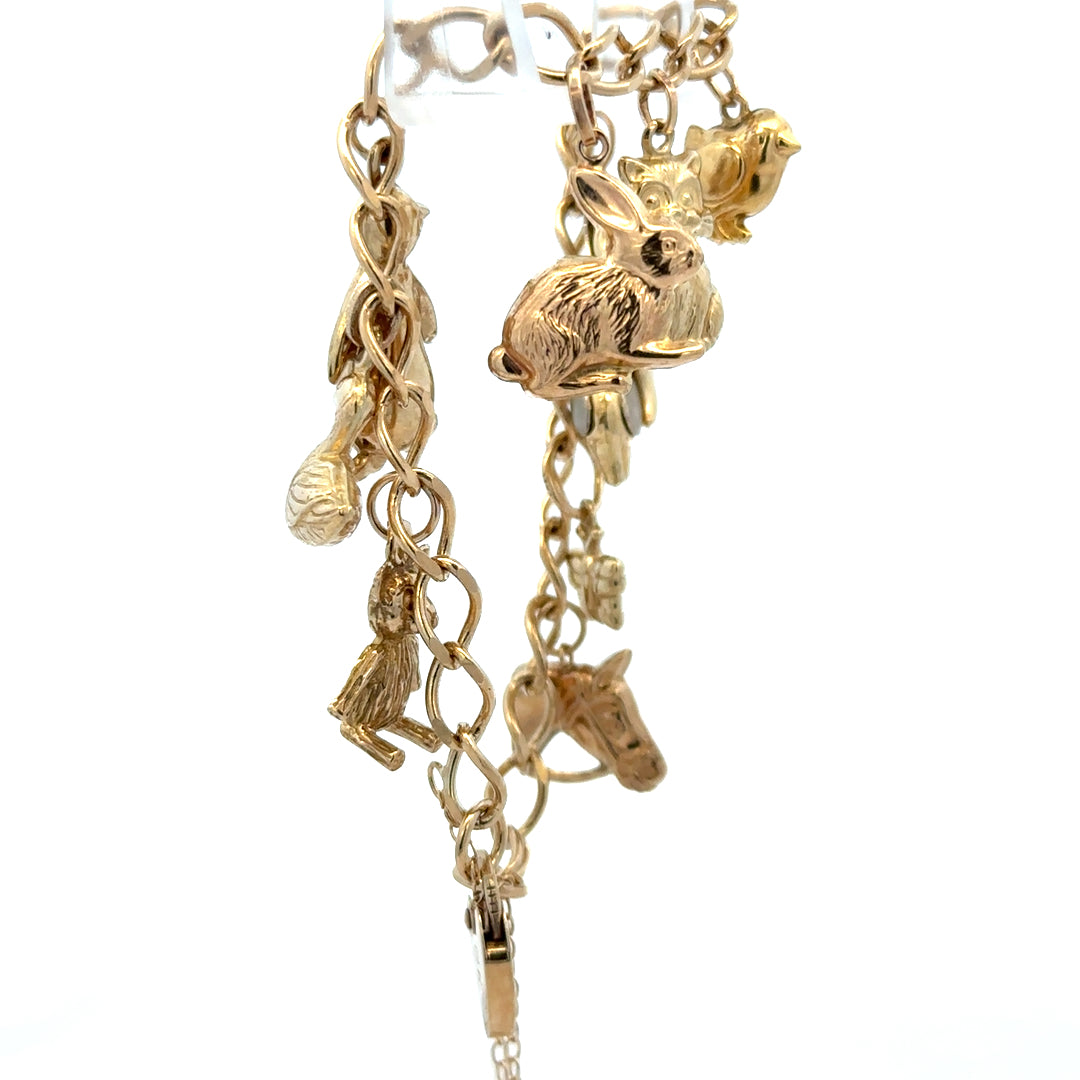 9ct yellow gold charm bracelet weighing 13.4g, featuring various engraved and decorative charms, by Reeves and Sons.