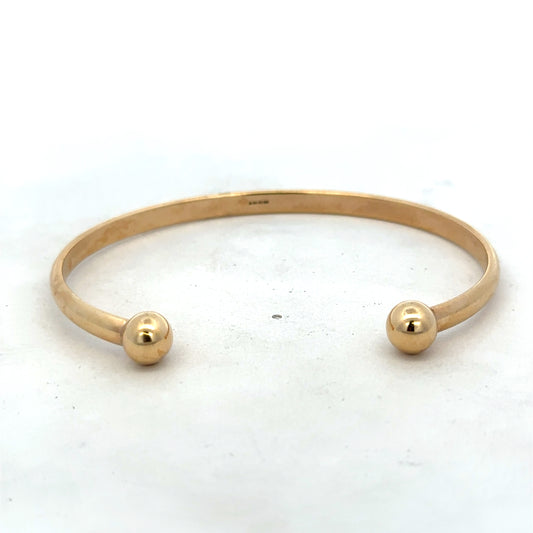 9ct yellow gold bangle bracelet weighing 16.1g, featuring a smooth, polished finish with Reeves and Sons branding.