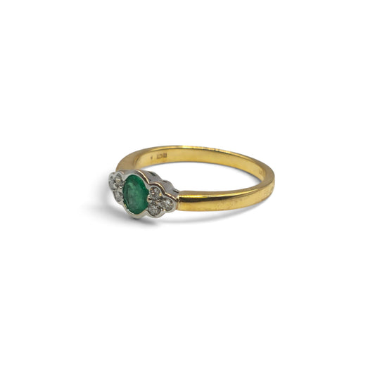 18ct yellow gold emerald and diamond ring by Reeves and Sons, showcasing a central emerald surrounded by sparkling diamonds.
