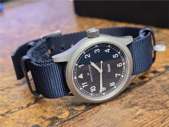 Hamilton Khaki watch Age 2025 with black dial, stainless steel case, and leather strap, displayed on a white background.