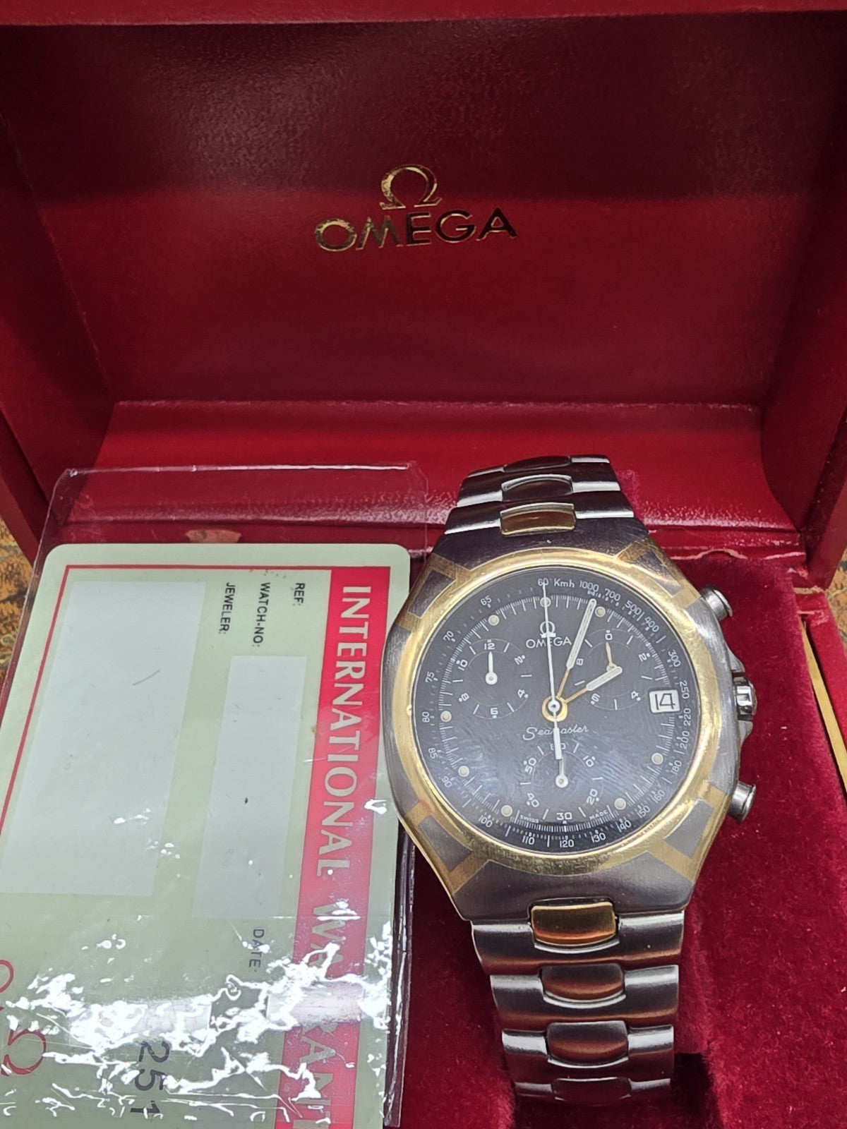 Omega Seamaster Polaris Chronograph watch with box and card, showcasing the timepiece's face and stainless steel bracelet.