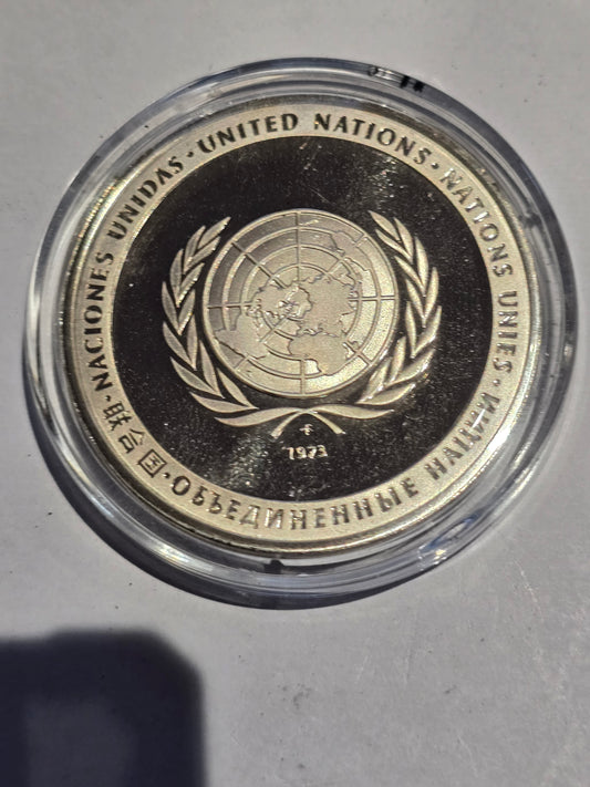 Sterling silver proof United Nations 1973 Peace Medal coin displayed in clear acrylic block, showcasing detailed design and craftsmanship.