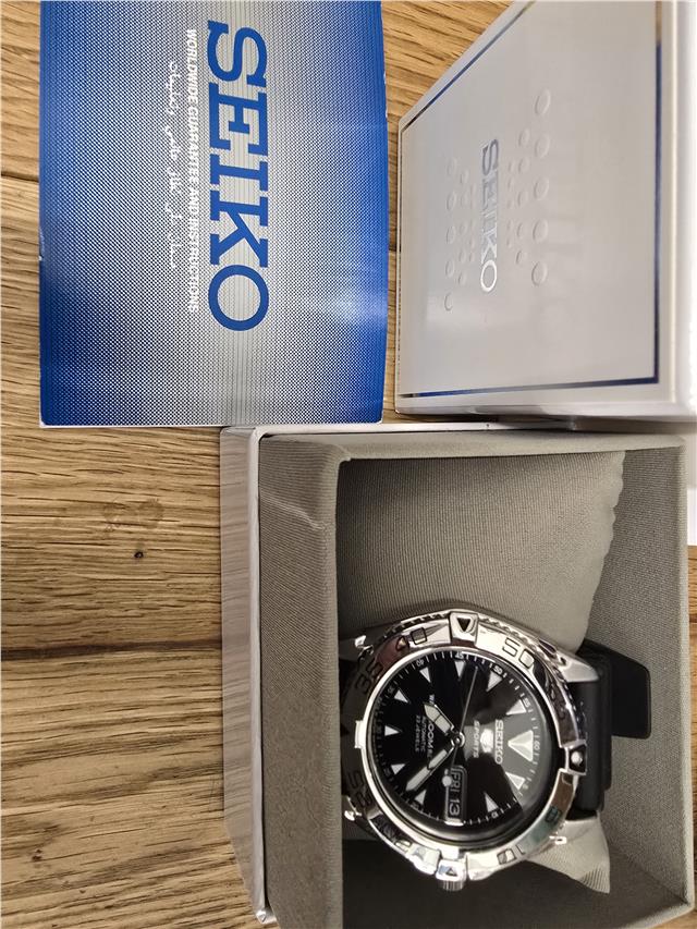 Seiko 5 Sports automatic watch with boxed papers, showing the watch face and stainless steel band.