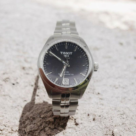 Tissot PR100 watch with box and papers, featuring a classic design and stainless steel band.