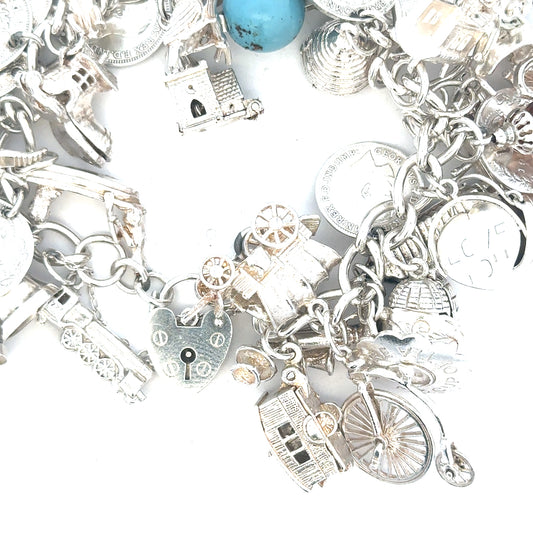 Silver charm bracelet with intricate designs, weighing 128.8g, featuring multiple charms and a secure clasp.