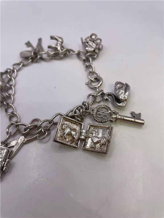 Silver charm bracelet with detailed charms, weighing 33.9g, featuring a stylish and versatile design.