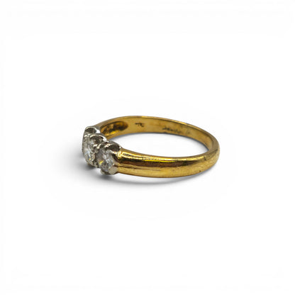 18ct yellow gold three stone diamond ring by Reeves and Sons, featuring a central diamond flanked by two smaller diamonds.