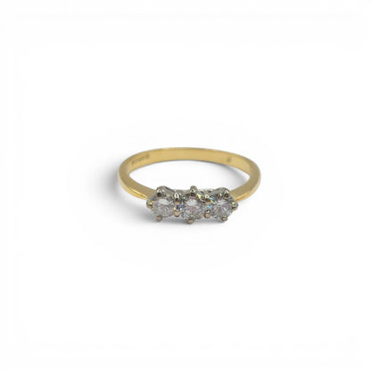 18ct yellow gold three-stone diamond ring by Reeves and Sons, featuring three sparkling diamonds and a polished gold band.