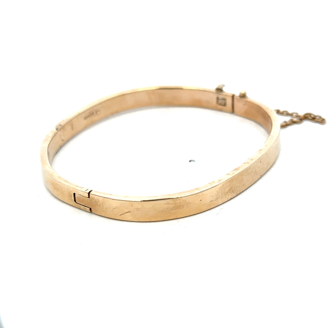 9ct yellow gold bangle weighing 24.1g with a smooth, polished finish, featuring a classic rounded design by Reeves and Sons.