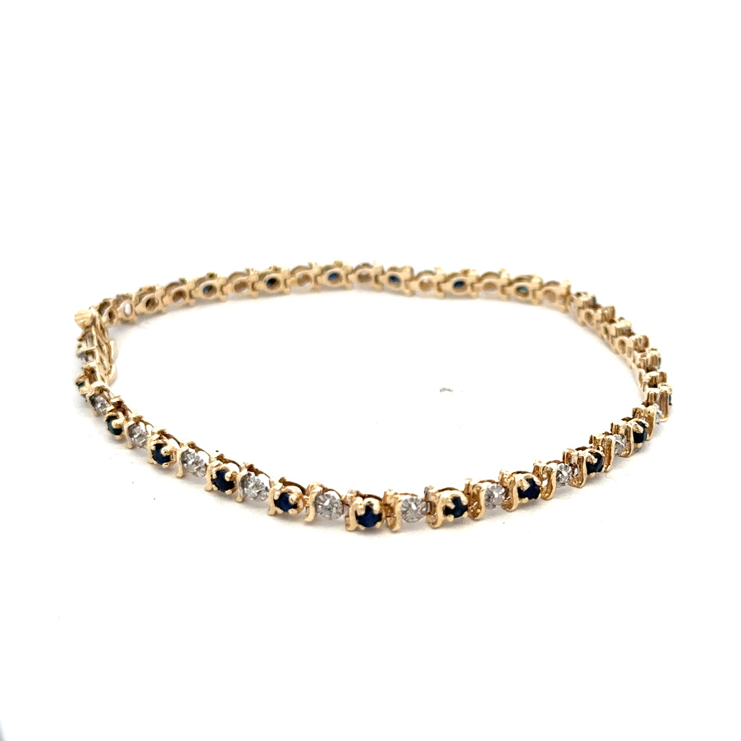 Reeves and Sons 9ct yellow gold sapphire and diamond bracelet showcasing blue sapphires and sparkling diamonds on a gold chain.