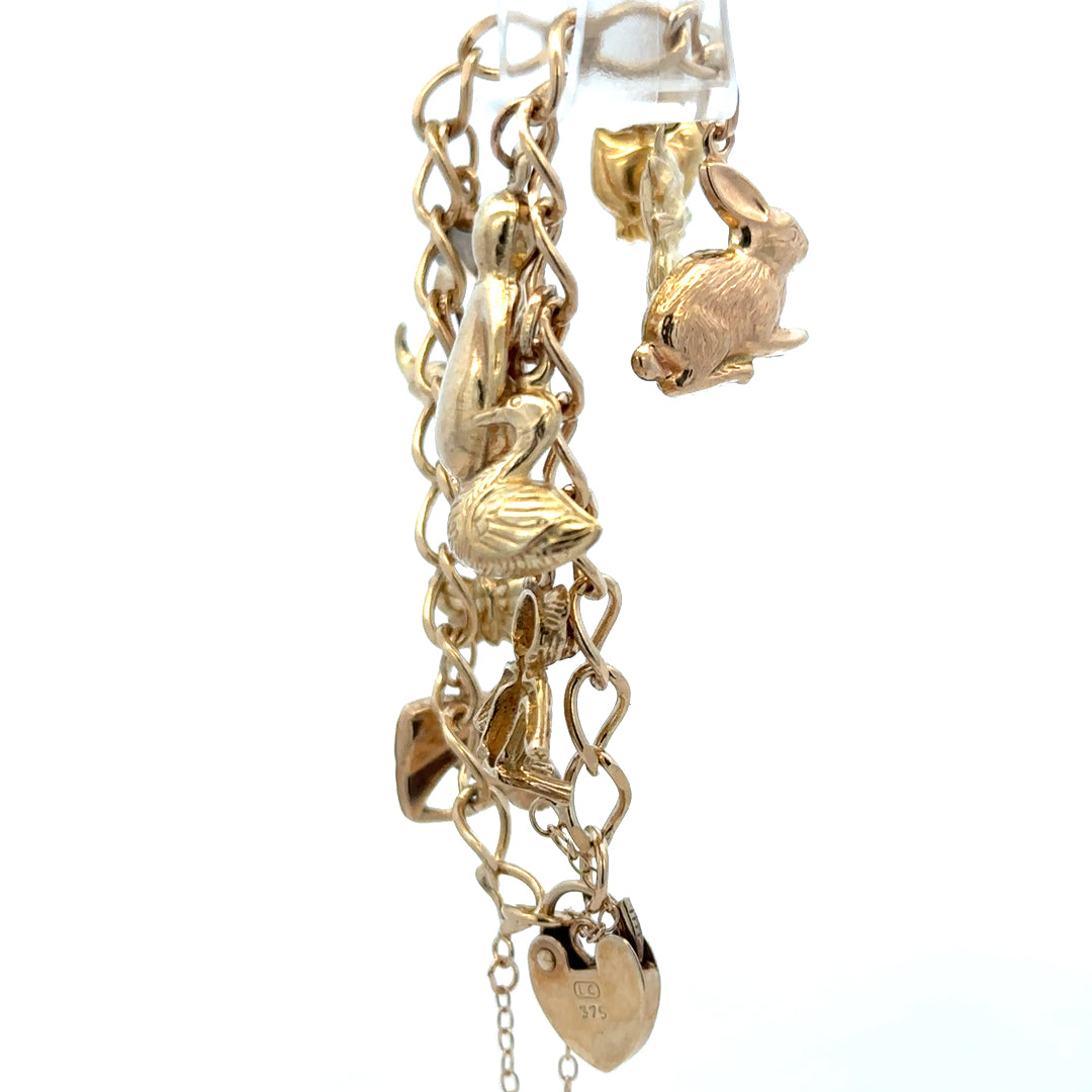 9ct yellow gold charm bracelet weighing 13.4g with various decorative charms, crafted by Reeves and Sons.
