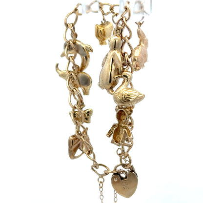 9ct yellow gold charm bracelet weighing 13.4g, featuring intricate charms and links, from Reeves and Sons.