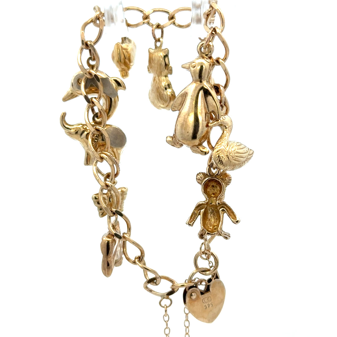 9ct yellow gold charm bracelet weighing 13.4g with intricate charms, crafted by Reeves and Sons.