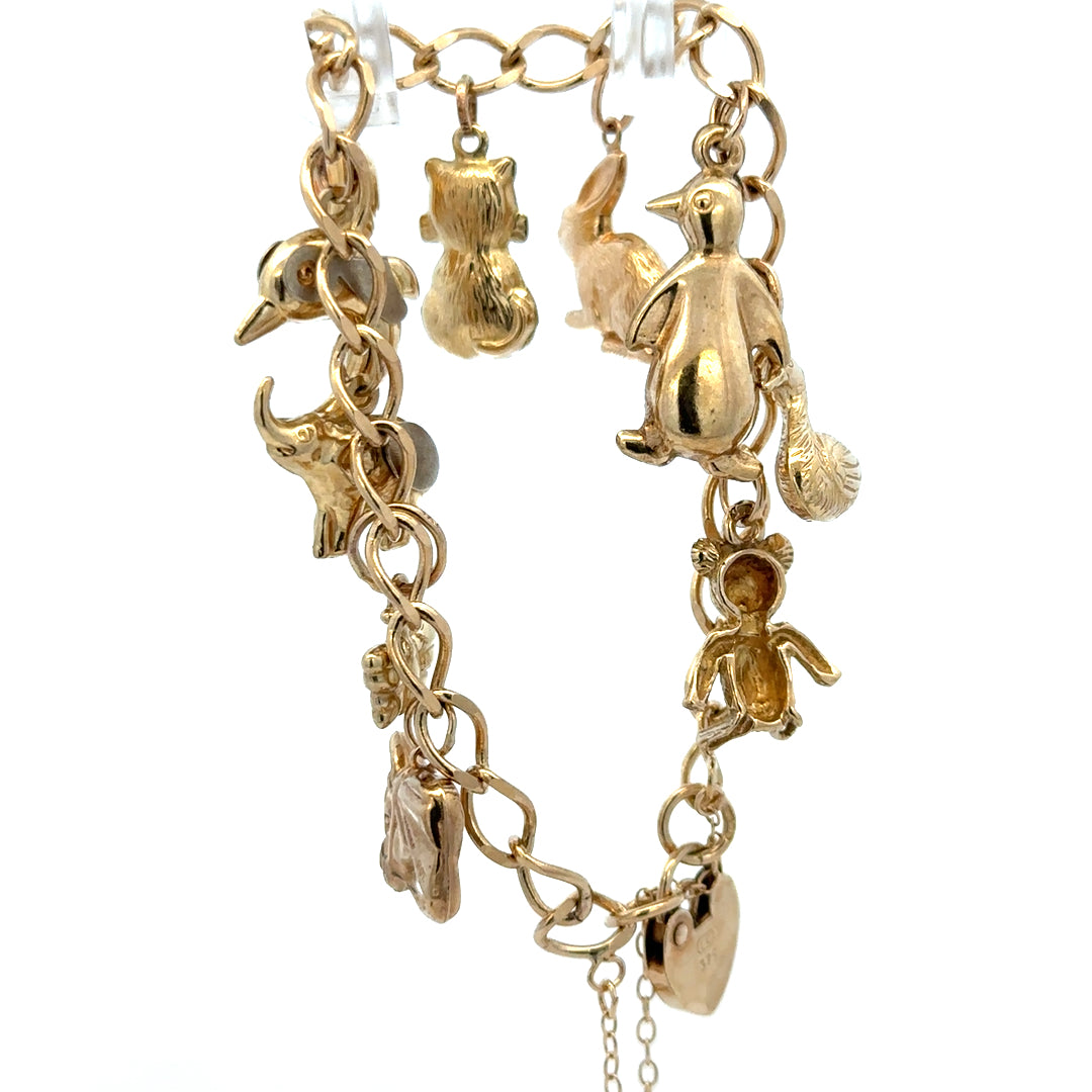 9ct yellow gold charm bracelet weighing 13.4g with intricate charm details, crafted by Reeves and Sons.