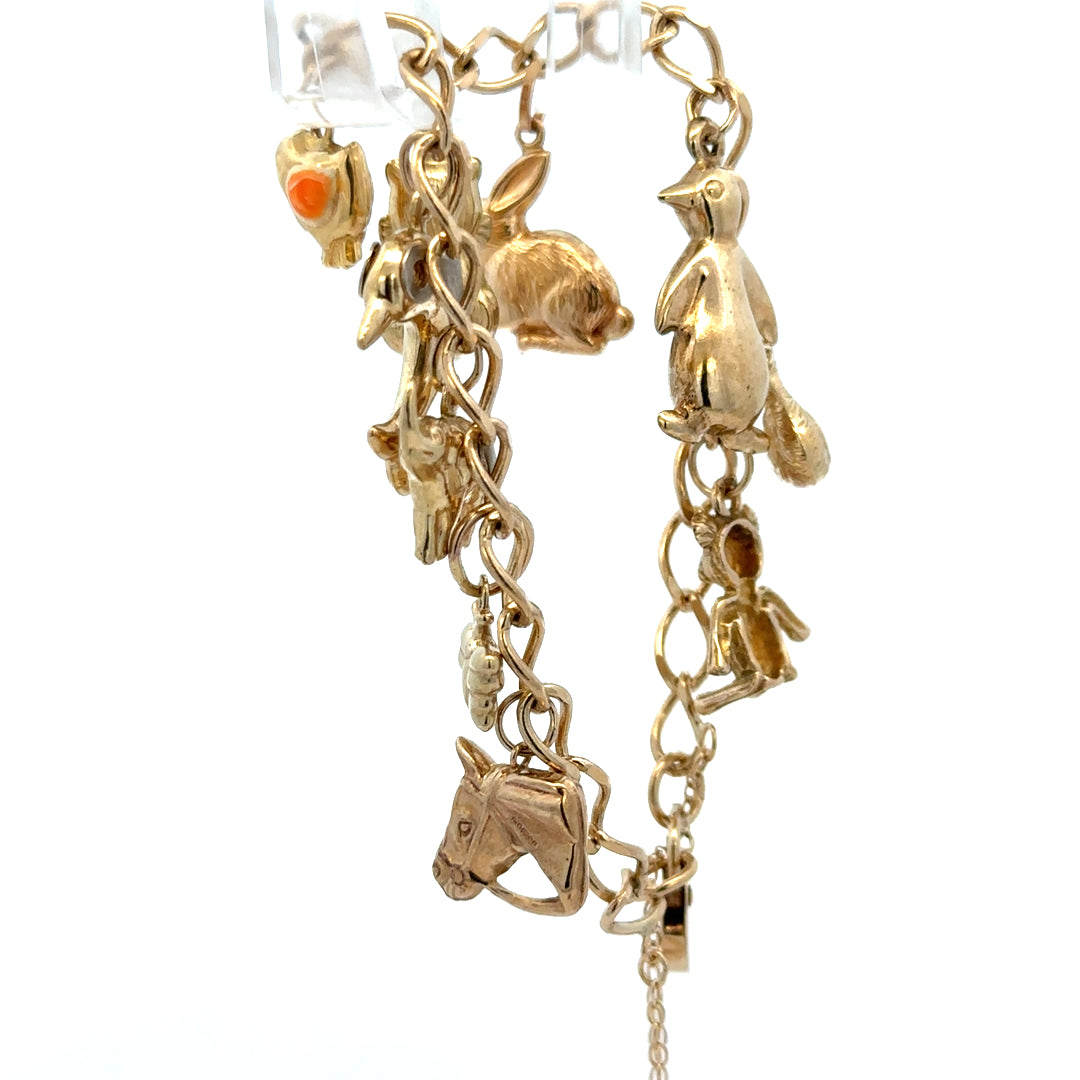 9ct yellow gold charm bracelet weighing 13.4g with various charms, crafted by Reeves and Sons, shown in close-up.