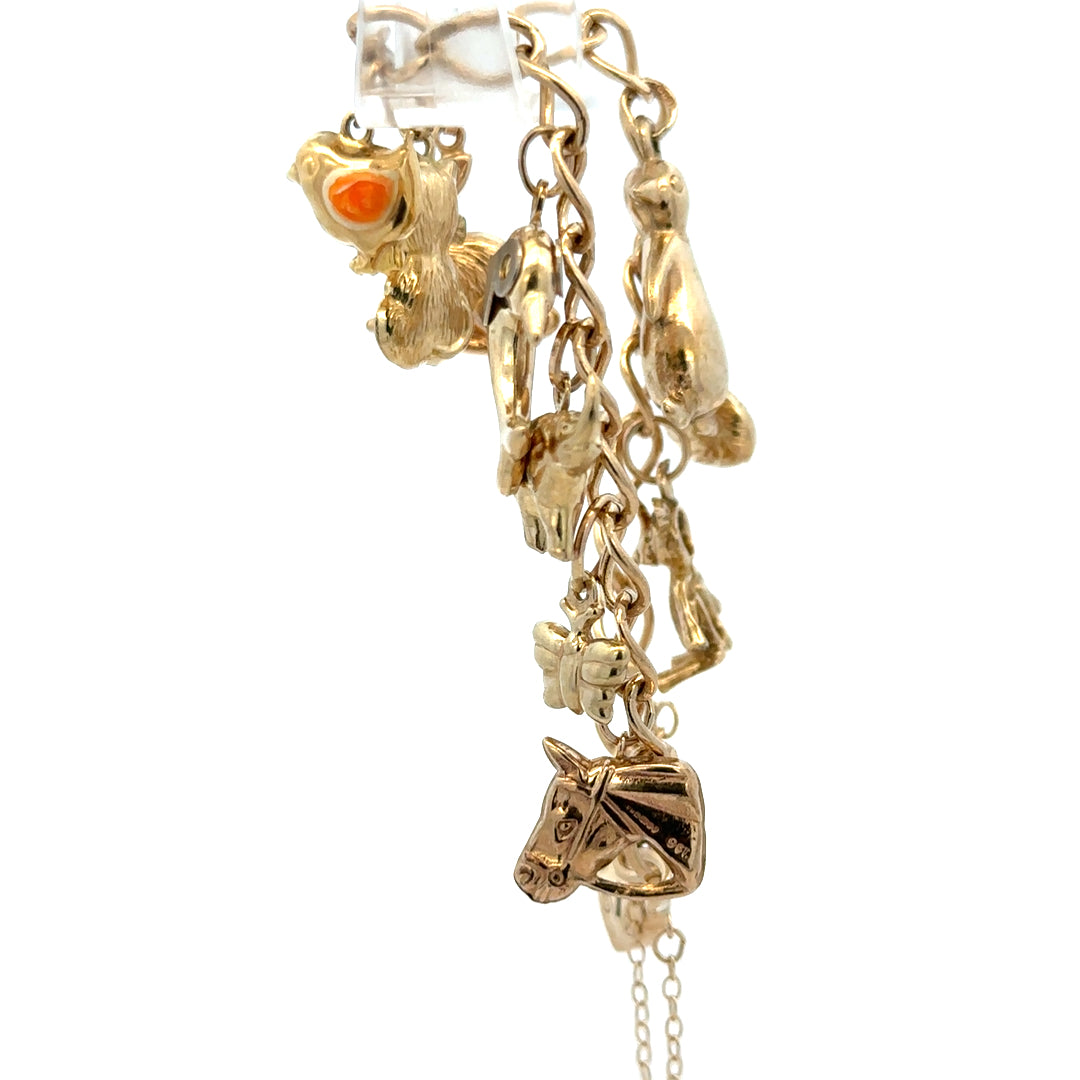 9ct yellow gold charm bracelet weighing 13.4g with various charms, crafted by Reeves and Sons.