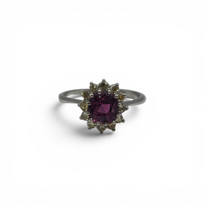 18ct white gold garnet and diamond ring by Reeves and Sons, featuring a central garnet gemstone surrounded by diamonds.