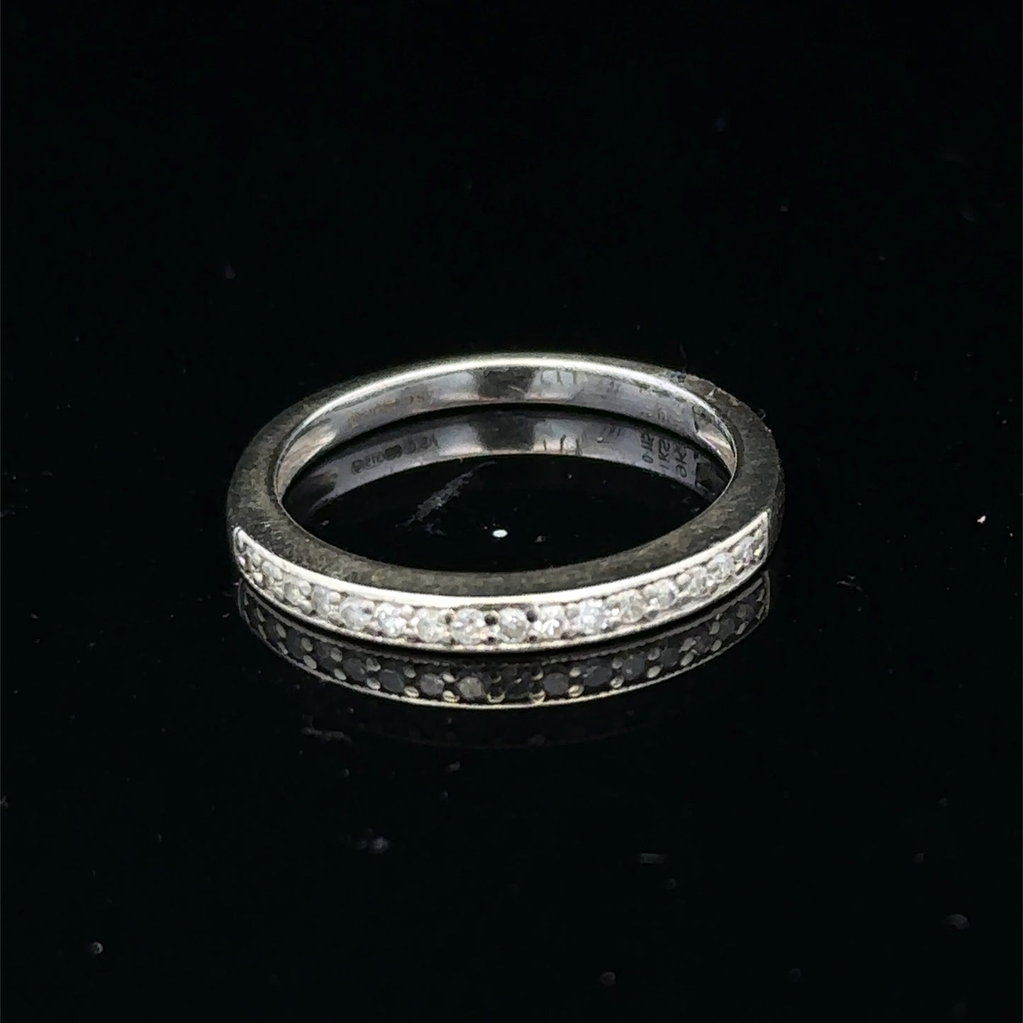 9ct white gold diamond half eternity ring with sparkling diamonds, crafted by Reeves and Sons, shown from a side angle.