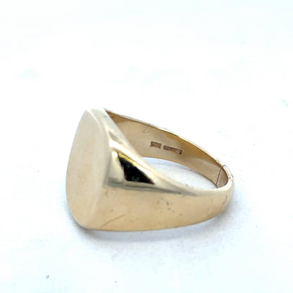 9ct yellow gold signet ring by Reeves and Sons, showcasing a polished gold band with a smooth, rounded face.