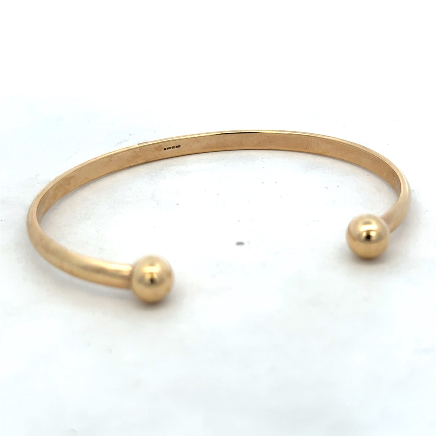 9ct yellow gold bracelet by Reeves and Sons, 16.1g, showcasing a smooth, polished bangle with subtle shine and classic design.