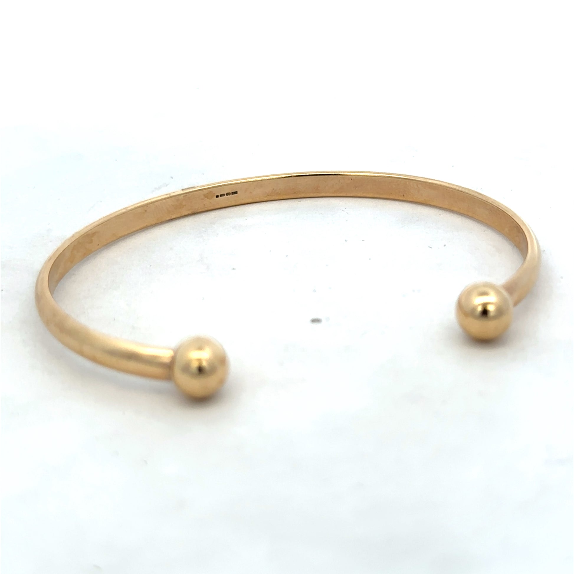 9ct yellow gold bracelet by Reeves and Sons, 16.1g, showcasing a smooth, polished bangle with subtle shine and classic design.
