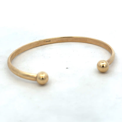 9ct yellow gold bracelet by Reeves and Sons, 16.1g, showcasing a smooth, polished bangle with subtle shine and classic design.