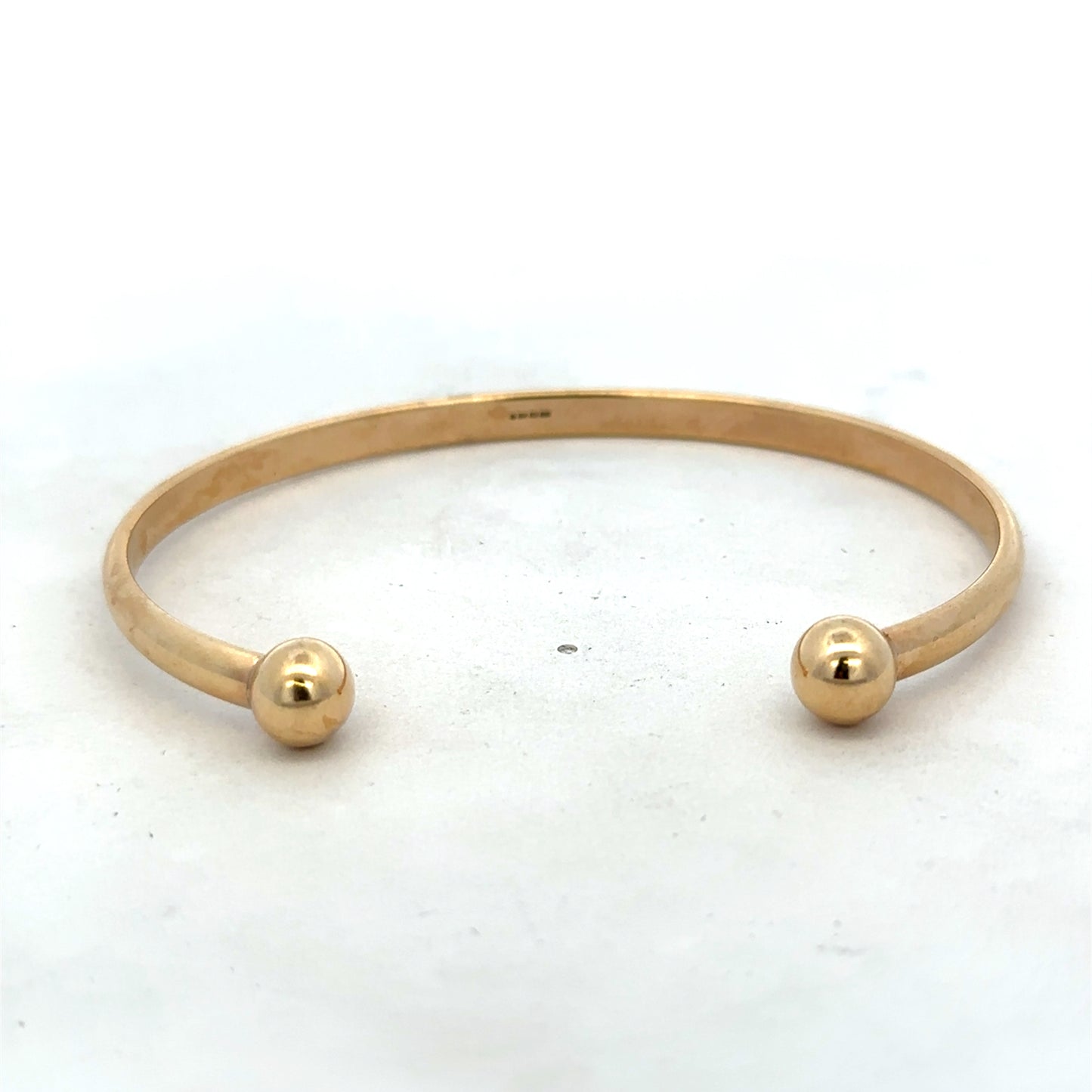 9ct yellow gold bangle bracelet weighing 16.1g, featuring a smooth, polished finish with Reeves and Sons branding.