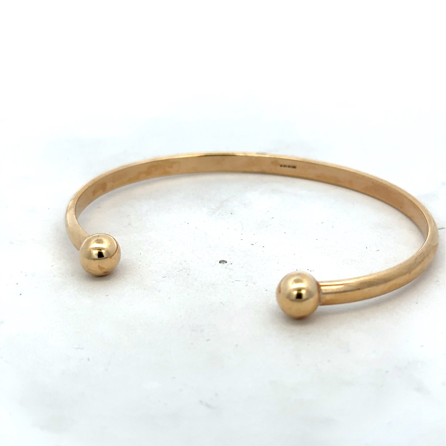 9ct yellow gold bangle bracelet weighing 16.1g with a smooth, polished finish, crafted by Reeves and Sons.