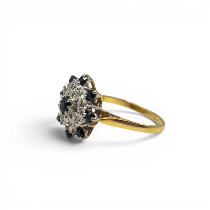 18ct yellow gold sapphire and diamond cluster ring with intricate design, featuring sparkling gemstones from Reeves and Sons.