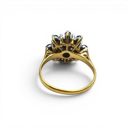 18ct yellow gold sapphire and diamond cluster ring by Reeves and Sons, featuring a vibrant sapphire centerpiece and sparkling diamonds.