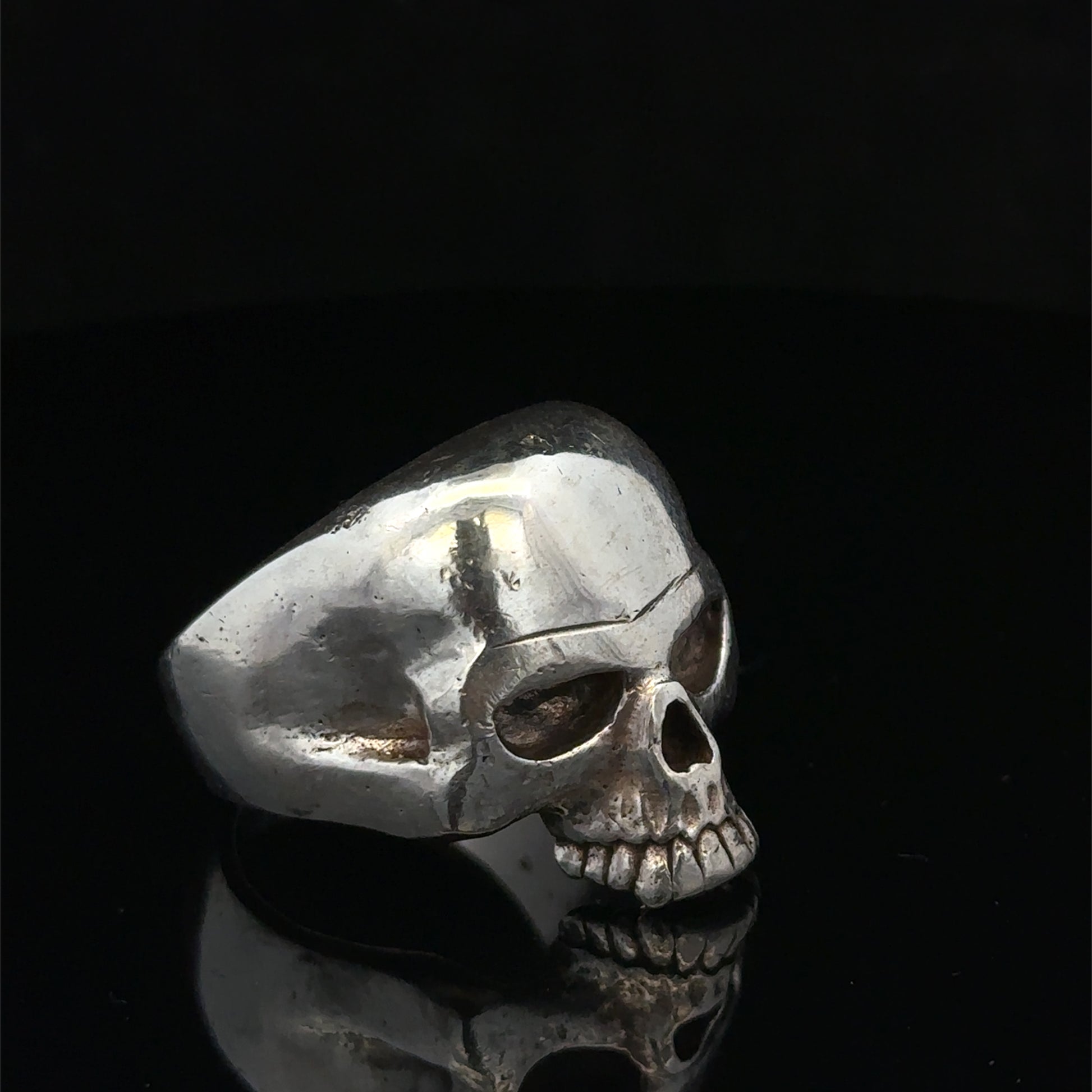 Silver skull ring by Reeves and Sons, size Z1, featuring a detailed skull design in polished metal.