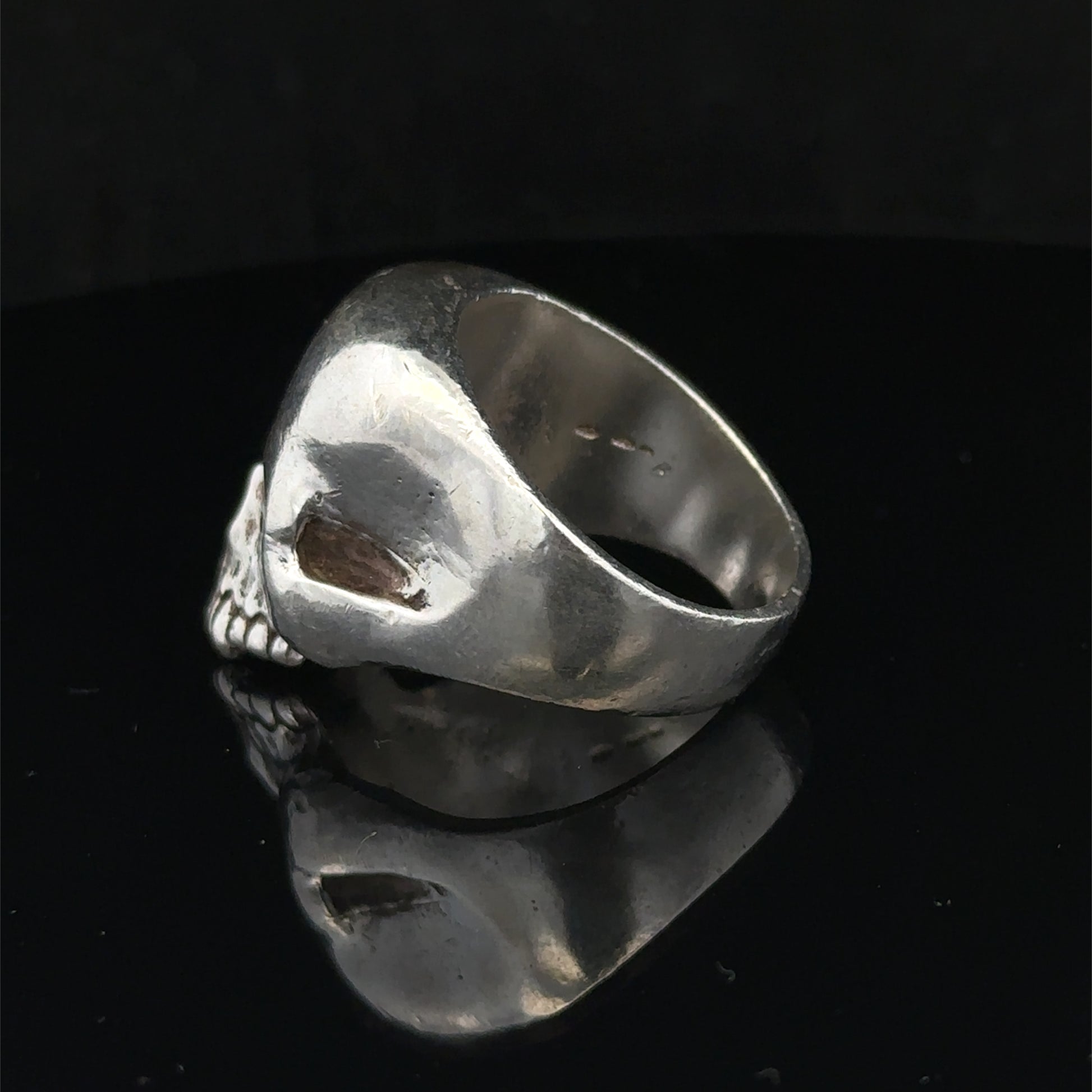 Silver skull ring by Reeves and Sons, size Z1, featuring detailed skull design, set against a plain background.