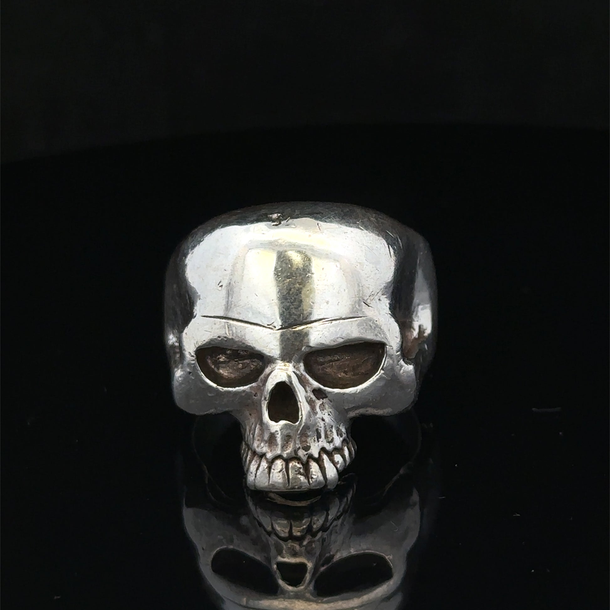 Silver skull ring in size Z1 by Reeves and Sons, featuring detailed skull design on a polished band.