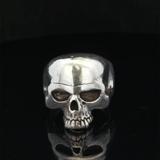Silver skull ring in size Z1 by Reeves and Sons, featuring detailed skull design on a polished band.