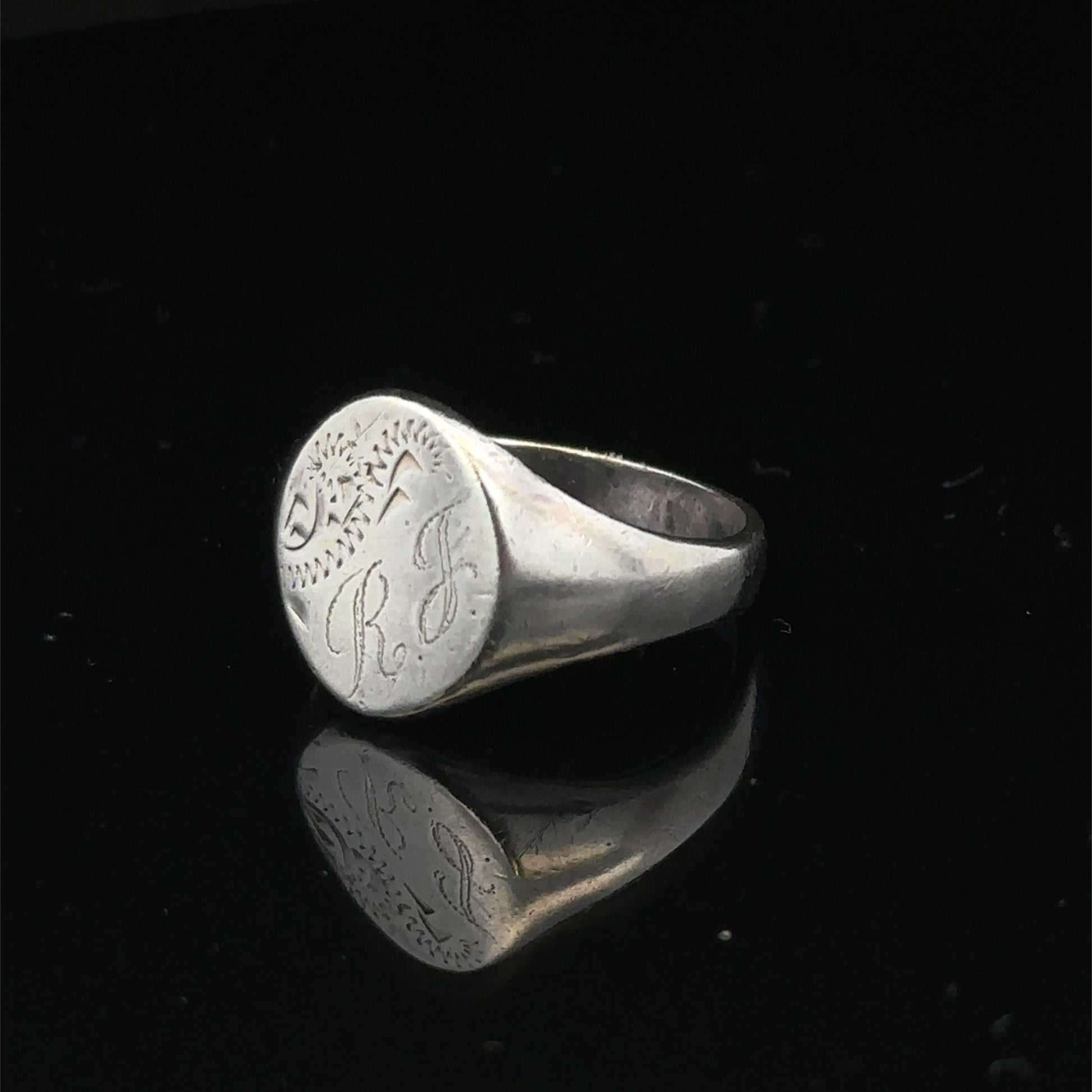 Silver signet ring from Reeves and Sons in size S1/2, featuring a polished band with engraved details.