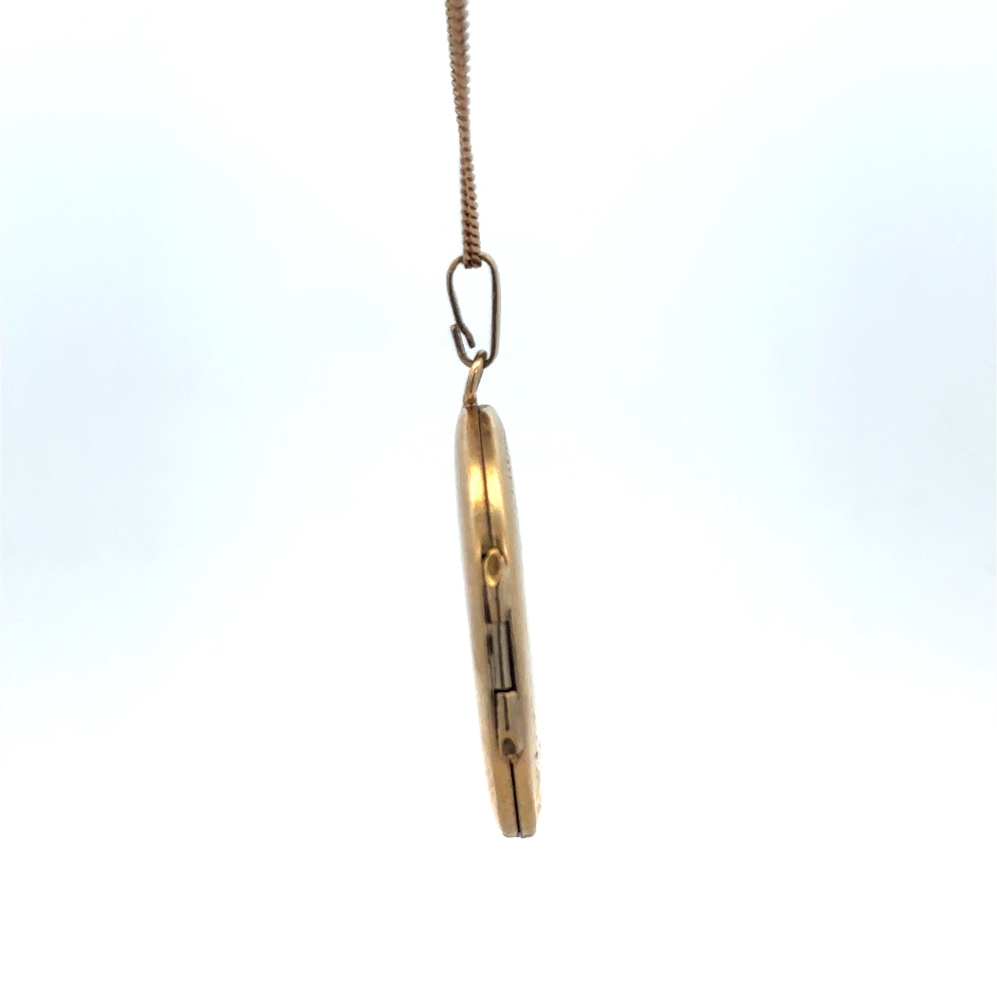 9ct yellow gold locket pendant with floral engraving, Reeves and Sons, weighing 5.4g, close-up view showing detailed craftsmanship.