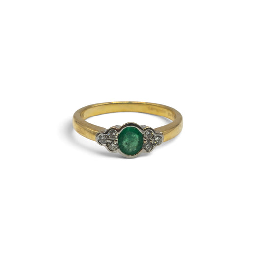 18ct yellow gold emerald and diamond ring by Reeves and Sons, featuring a central emerald gemstone and sparkling diamonds.