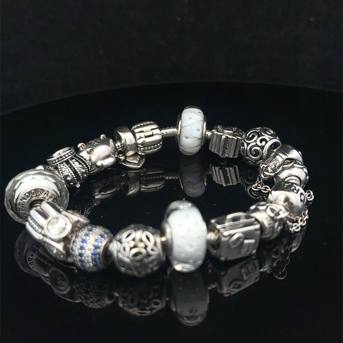 Silver Pandora charm bracelet by Reeves and Sons featuring intricate charms and a secure clasp, weighs 69.8g.
