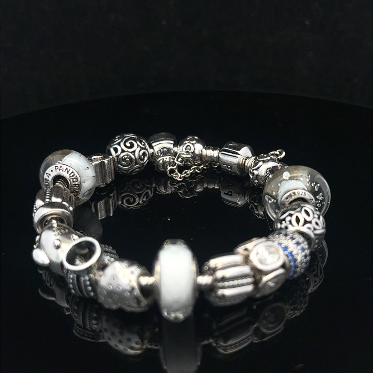 Silver Pandora charm bracelet by Reeves and Sons, weighing 69.8g, featuring detailed charms and classic bracelet design.
