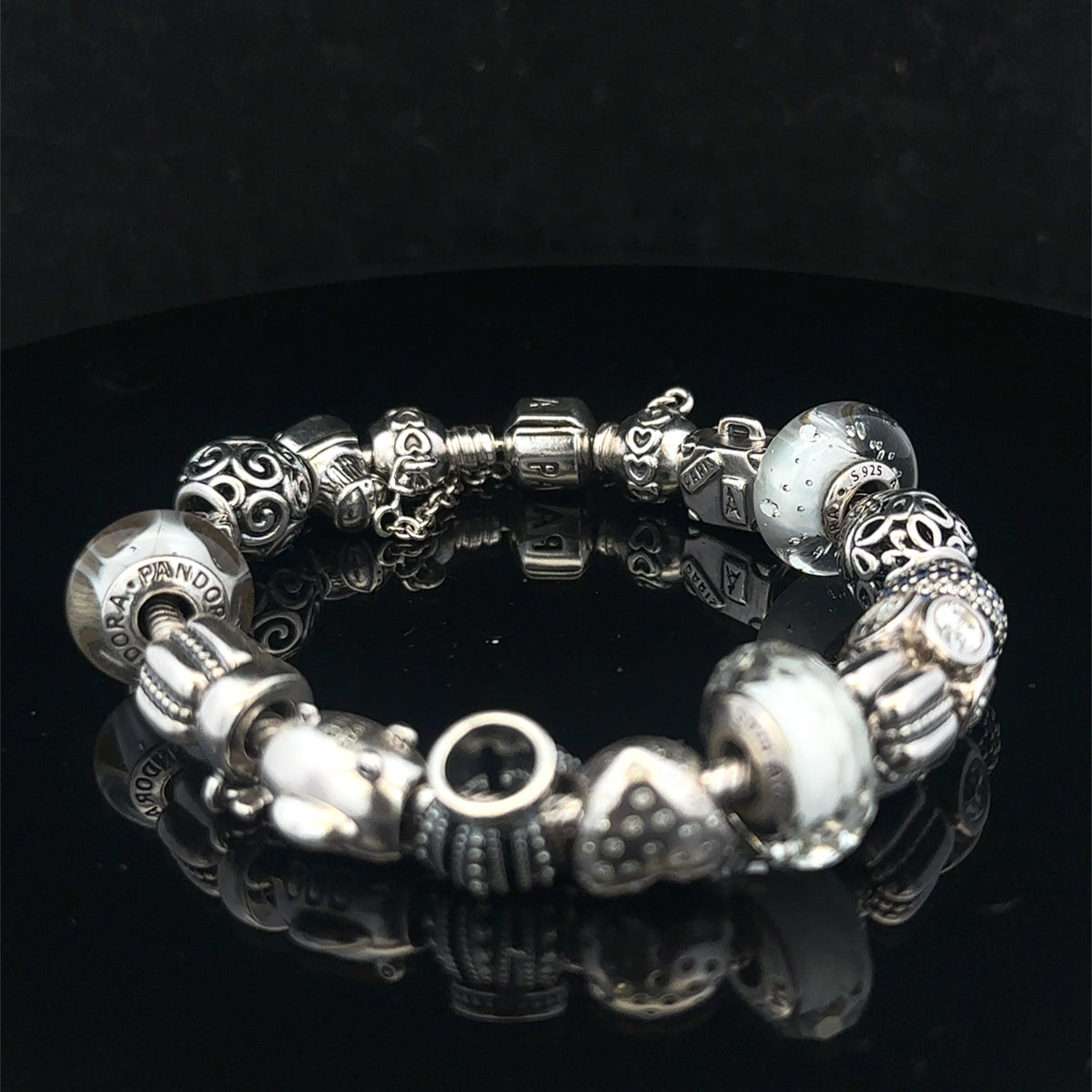 Silver Pandora charm bracelet by Reeves and Sons with intricate links, weighing 69.8g, featuring detailed charm accents.