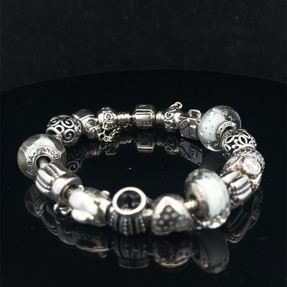 Silver Pandora charm bracelet by Reeves and Sons with intricate links, weighing 69.8g, featuring detailed charm accents.