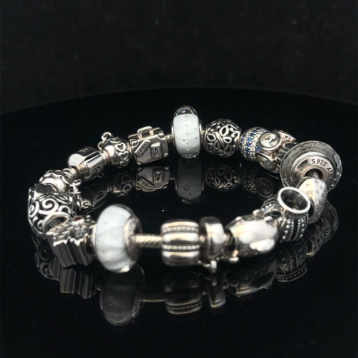 Silver Pandora charm bracelet by Reeves and Sons, weighs 69.8g, featuring intricate designs and multiple charms on a classic bracelet.