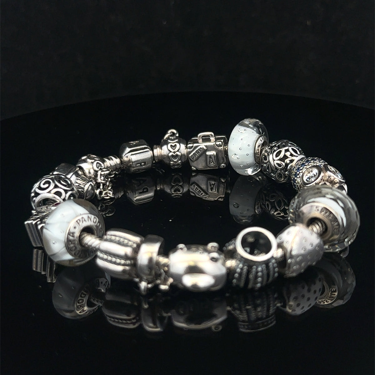 Silver Pandora charm bracelet by Reeves and Sons with intricate detailing, weighing 69.8g, displayed on a neutral background.