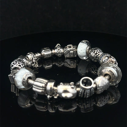 Silver Pandora charm bracelet by Reeves and Sons with intricate detailing, weighing 69.8g, displayed on a neutral background.