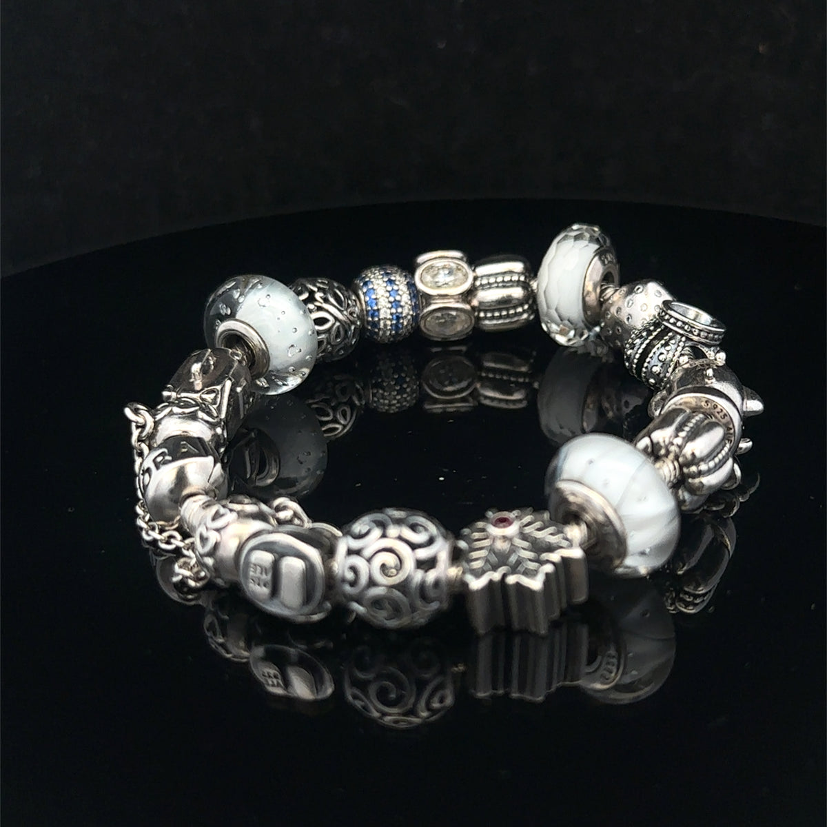 Silver Pandora charm bracelet by Reeves and Sons, weighing 69.8g, featuring detailed charms and a secure clasp.