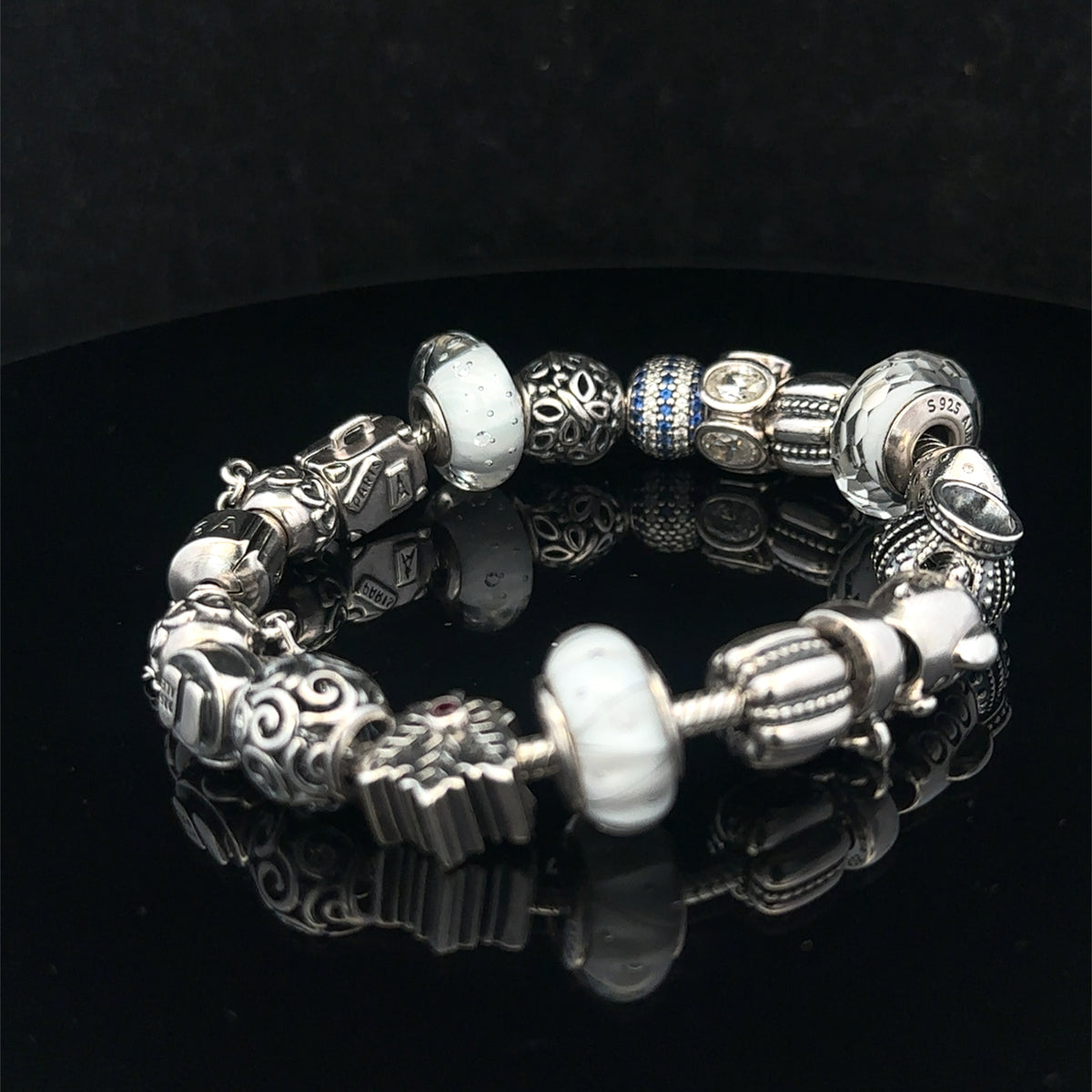 Silver Pandora charm bracelet by Reeves and Sons, weighing 69.8g, with intricate charms and a clasp detail.
