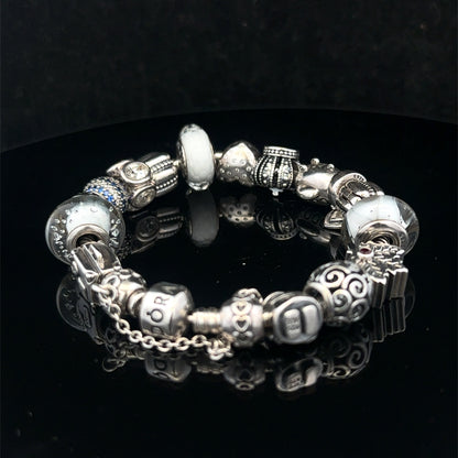 Silver Pandora charm bracelet by Reeves and Sons, weighing 69.8g, with intricate charms and detailed silver design.