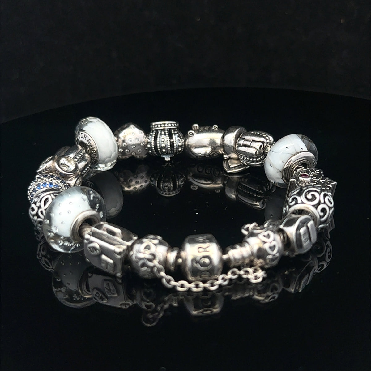 Silver Pandora-style charm bracelet by Reeves and Sons with intricate links and decorative charms, weighs 69.8g.